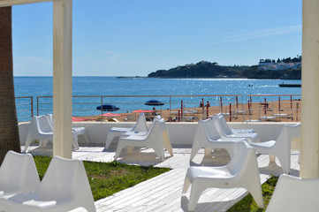 Beach view with restaurant chairs, blue sunny outdoors background seaside