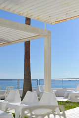 Relaxing background ocean beach view with table chairs, sunshine blue sky