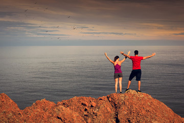 Détente en extérieur face à la mer: homme et femme levant les bras au ciel