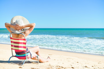 Fototapeta na wymiar Back view of female sunbathe relaxing, sunny summer beach outdoors vacation 