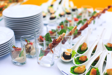 Fototapeta na wymiar Beautifully decorated catering banquet table with different food snacks and appetizers with sandwich, caviar, fresh fruits on corporate christmas birthday kids party event or wedding celebration