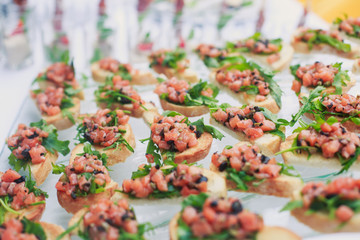 Beautifully decorated catering banquet table with different food snacks and appetizers with sandwich, caviar, fresh fruits on corporate christmas birthday kids party event or wedding celebration