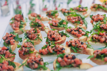 Beautifully decorated catering banquet table with different food snacks and appetizers with sandwich, caviar, fresh fruits on corporate christmas birthday kids party event or wedding celebration
