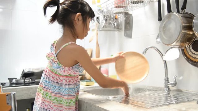 Asian girl help her mother for dish washes in the kitchen.
