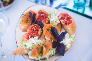 Beautifully decorated catering banquet table with different food snacks and appetizers with sandwich, caviar, fresh fruits on corporate christmas birthday kids party event or wedding celebration