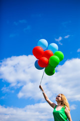 Happy young woman in green dress holding colorful balloons and flying over a panorama of old Kiev, Ukraine