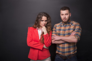 Portrait of confident business man and woman posing in studio. Freelancers posing with their arms crossed over black background.