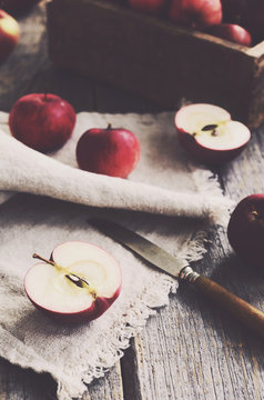 Cutting apples with knife on wooden background