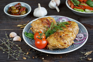 Roasted chicken and vegetables on dark wooden background