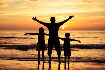 Father and children  playing on the beach at the sunset time.