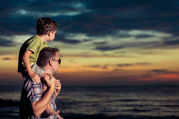 Father and son  playing  on the beach at the sunset time.