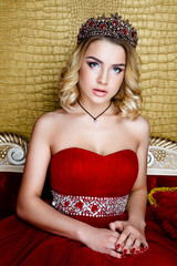Fashion shoot of beauty young queen long blond hair crown on her head  in a long red dress  
