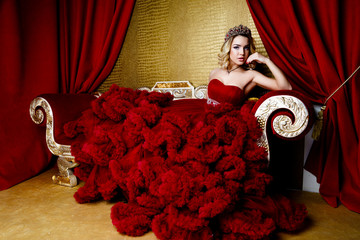 Fashion shoot of beauty young queen long blond hair crown on her head  in a long red dress  