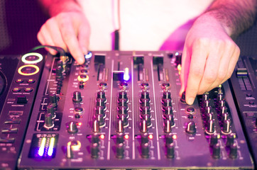 Dj mixes the track in the nightclub at party - music and technology concept