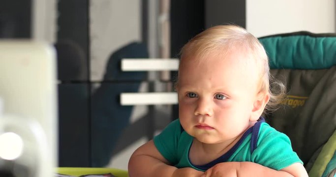 Little Baby Boy Watching Cartoons on an Tablet in the Kitchen of His House