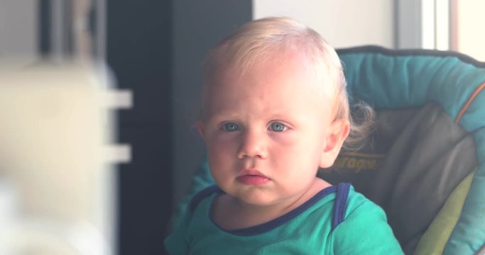 Little Baby Boy Watching Cartoons on an Tablet in the Kitchen of His House