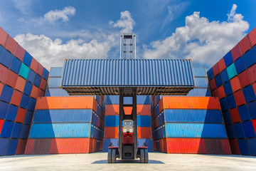 Forklift truck lifting cargo container in shipping yard for transportation import, export and blue...