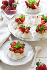 Homemade small strawberry pavlova meringue cakes with mascarpone cream and fresh mint leaves on white plate