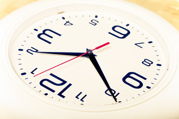 White wall clock with black arrows. Selective focus. Shallow dep