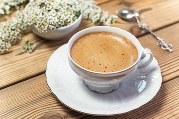 Vintage cup of coffee and flowers on wooden table
