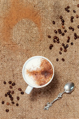 Cup coffee latte, coffee beans and a spoon on burlap