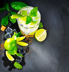 Mojito cocktail on a table. Summer cocktail with rum, lime, mint, ice cubes and brown sugar