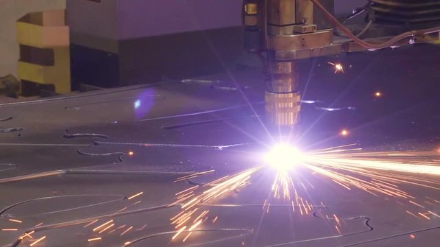 Big sparks coming from the plasma cutter while making a pattern out of the big metal sheet