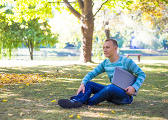 Obraz premium Student using his laptop in autumn city park
