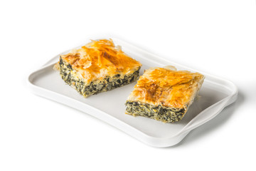 Piece of Greek pie spanakopita on the white plate on the white background