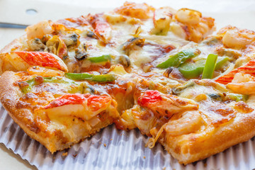 Seafood Italian Pizza slice in paper box.