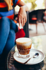 Coffee on the table with a woman sitting in the background