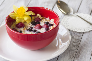 Red bowl of cereal with strawberries with berries