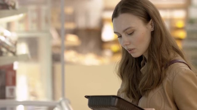 Female customer chooses the semi-finished products which are stored in the refrigerator
