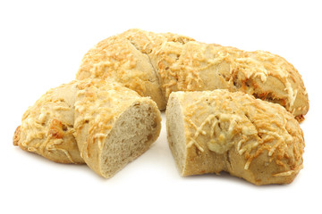 freshly baked spelt bread covered with grated cheese and a cut one on a white background