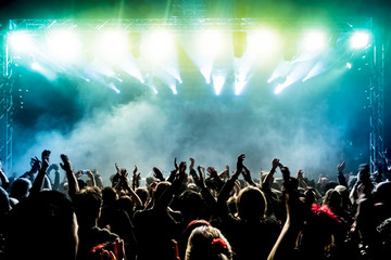 silhouettes of concert crowd in front of bright stage lights