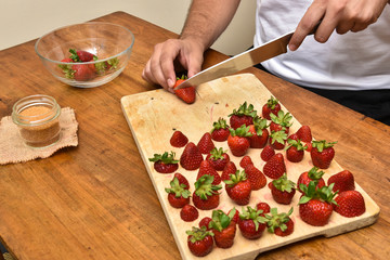 Man slicing strawberries on a wooden table