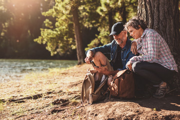 Mature couple stops to check their position while hiking
