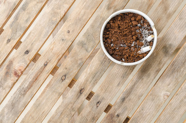 Cigarette and coffee ground in a ceramic ashtray and on wood tab