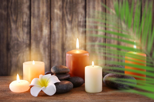 Spa stones with burning candles and flowers on wooden background