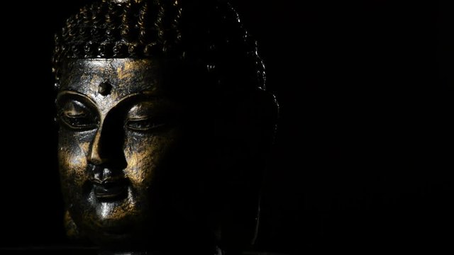Buddha face, deity buddhist, rotating at black background justify at left