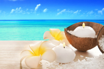 Obraz na płótnie Canvas Spa concept of plumeria, coconut and candles with sea salt on seascape background