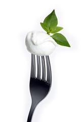 Mozzarella cheese skewered in fork with basil leaf