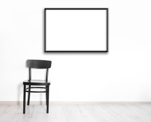 Black chair and empty picture frame on wall background