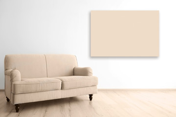 Cozy couch and empty picture frame on wall background