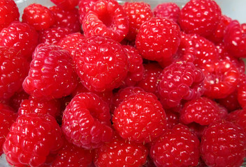 Ripe red raspberries in a basket in a heap