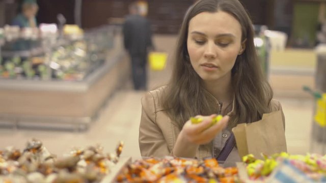 Nice girl chooses sweets at the supermarket