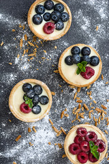 Delicious tartlets with raspberries and blueberries on slate background
