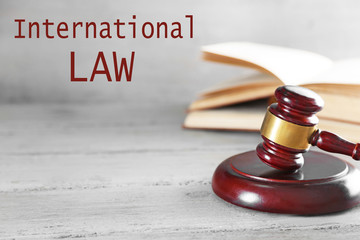 Gavel and books on wooden table on grey background. International law concept