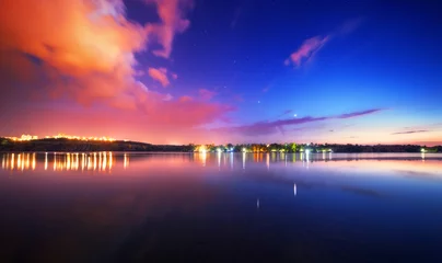 Papier Peint photo Nuit Colorful night landscape on the lake with blue sky and moving clouds reflected in water. Nature background