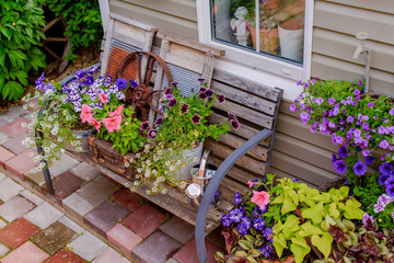 Beautifully decorated porch of a private house, colorful flowers in large clay pots, vintage bench,...